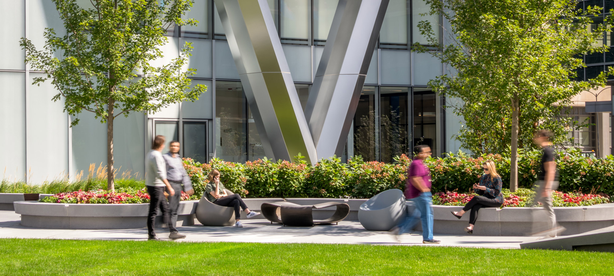 Pedestrians walking on the sidewalk around a green outdoor park