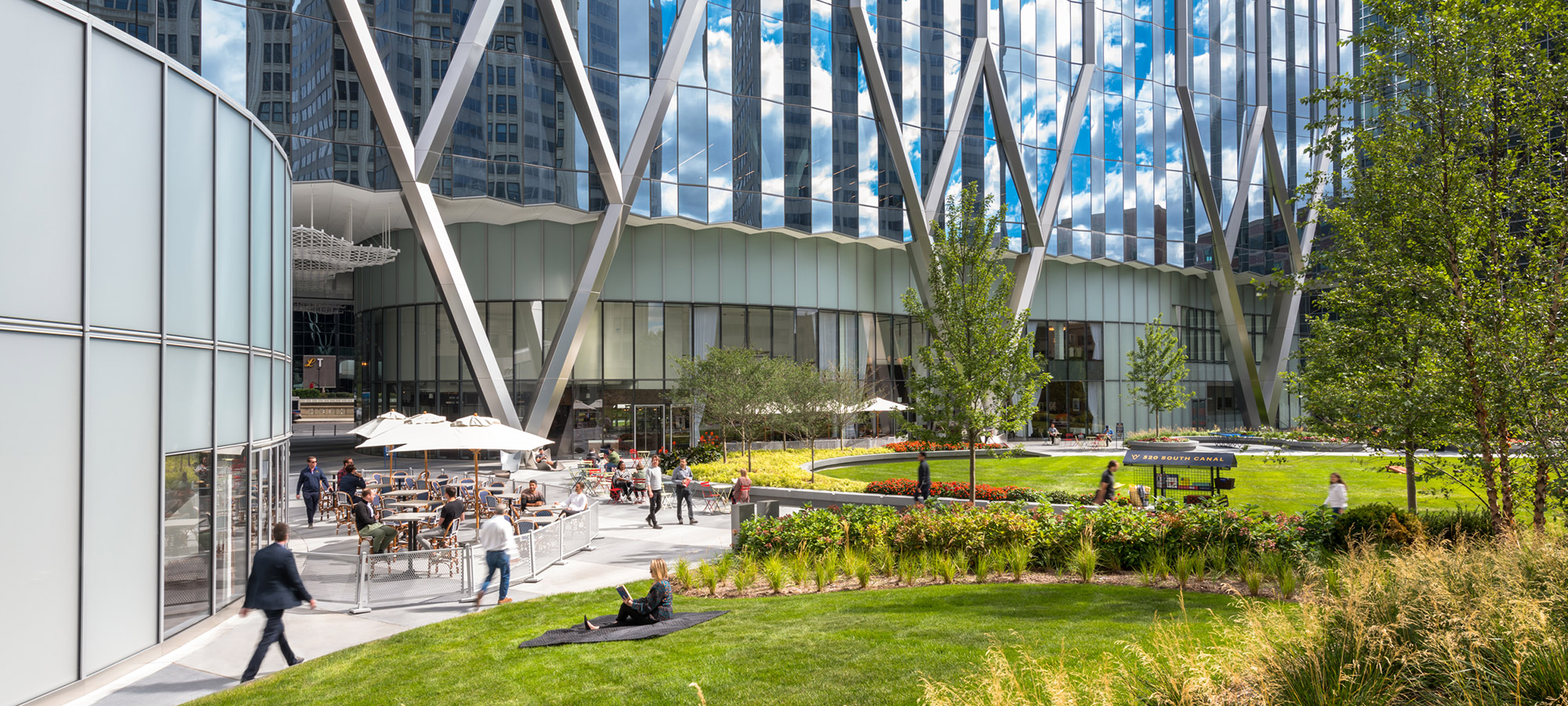 People enjoying an nice city park with trees, grass and seating