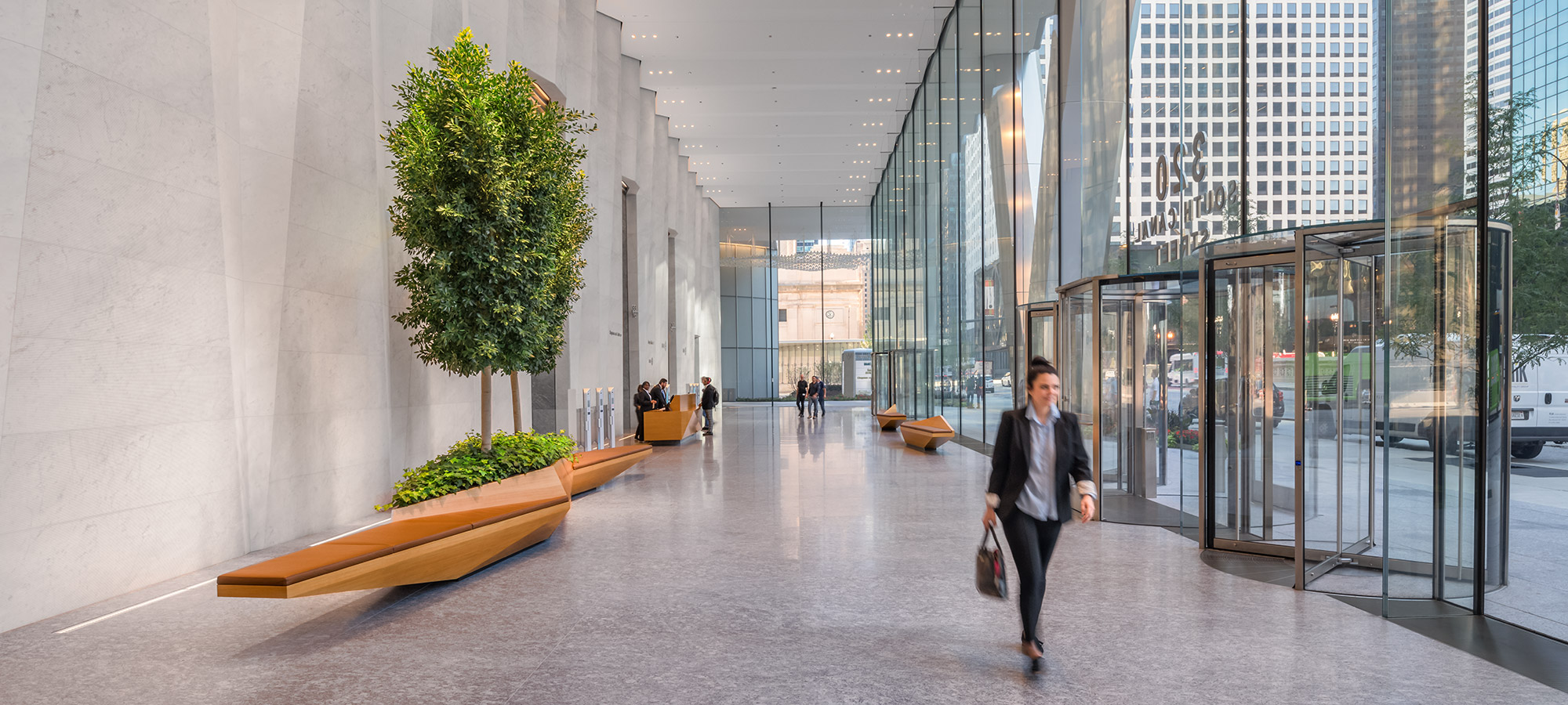 A glass entryway and lobby with geometric walls and wood benches